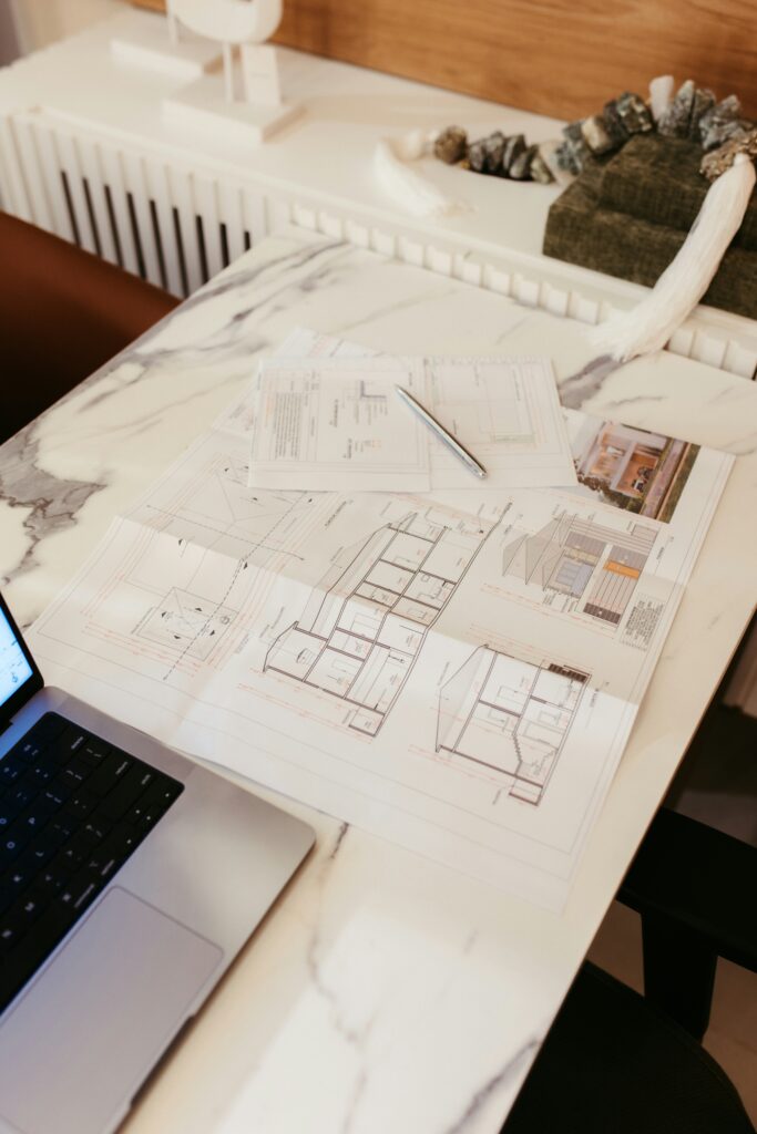 Dimensioned interior drawings spread across a marble-topped work table