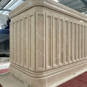 Beige marble architectural component with shaped edges and recessed panels